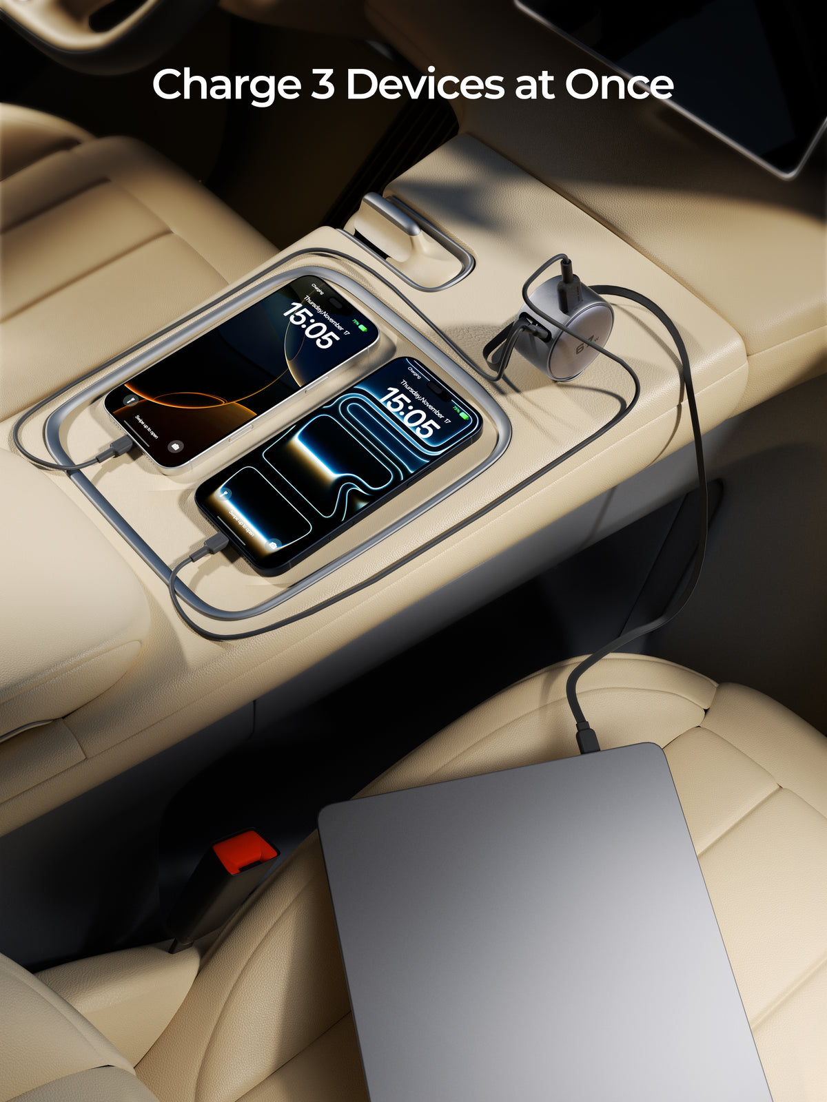 A car center console charging setup with a silver metal ring charger station holding two smartphones, plus a laptop on the seat and the text 'Charge 3 Devices at Once' at the top.